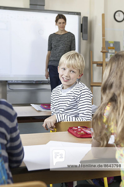 Junge im Klassenzimmer sitzend,  lächelnd