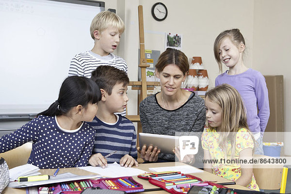 Lehrer mit digitalem Tablett mit Schülern im Klassenzimmer