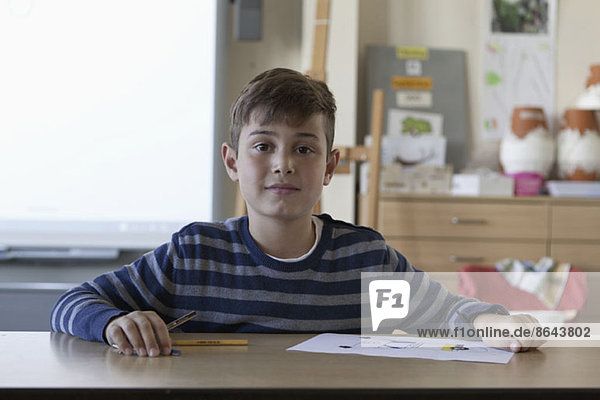 Junge mit Zeichenpapier im Klassenzimmer,  Portrait
