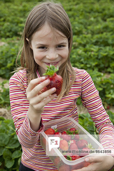 Porträt eines Mädchens mit Erdbeerdose  lächelnd