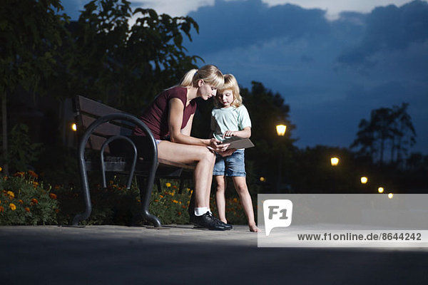Mutter und Tochter mit digitalem Tablett im Park