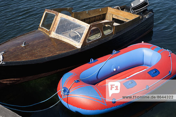 A retro motorboat moored next to a new inflatable boat