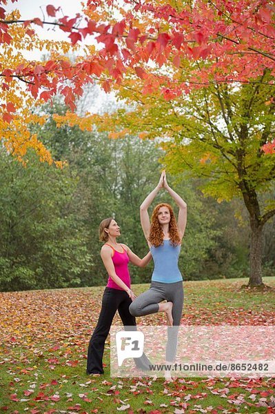 Yogalehrerin unterrichtet junge Frau im Wald