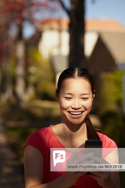 Junge Frau im Sonnenschein beim Blick aufs Handy