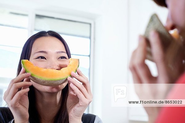Zwei junge Frauen in der Küche mit Melonenmündern
