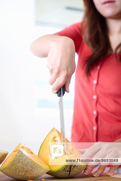 Junge Frau in der Küche beim Schneiden von Melone