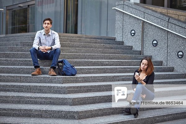 Ein unglückliches Paar sitzt auf einer Treppe.