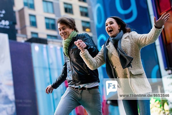 Young couple running on street  New York City  USA