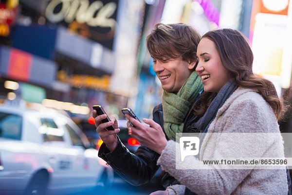 Young couple competing on cell phones  New York City  USA