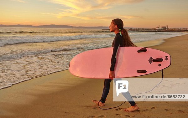Mädchen am Strand mit rosa Surfbrett