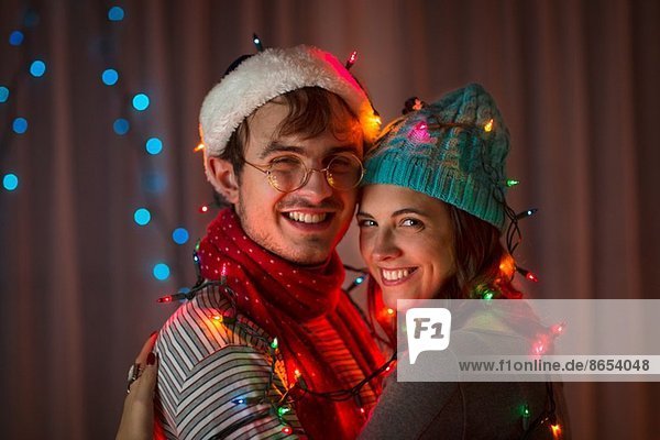 Junges Paar in dekoratives Licht gehüllt zu Weihnachten