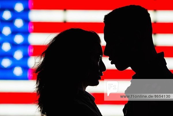 Silhouette of young couple in front of American flag
