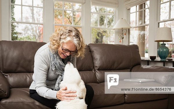 Seniorin mit Labradorhund im Wohnzimmer