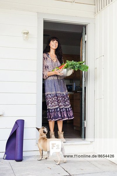 Junge Frau in der Tür mit einer Schüssel mit Gemüse