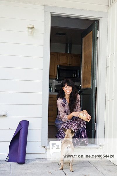 Junge Frau sitzend in der Tür mit Hund