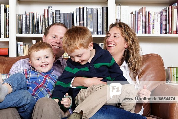 Mid adult parents and young sons sitting on sofa