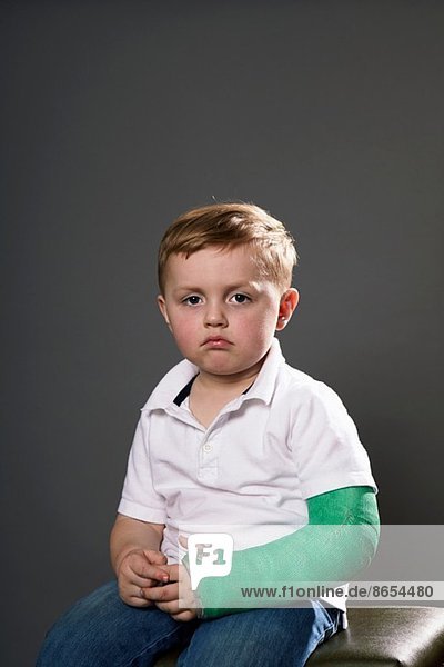 Porträt eines mürrischen Jungen mit Gipsabdruck am Arm