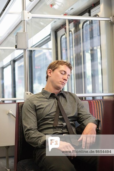 Mittlerer Erwachsener Büroangestellter schlummert auf Zugfahrt