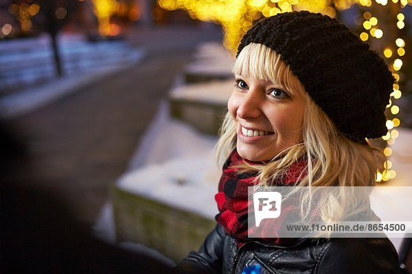 Junge Frau auf der Stadtstraße mit Weihnachtsbeleuchtung
