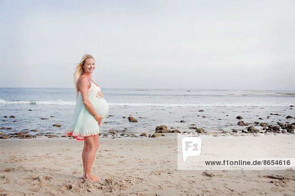 Portrait of pregnant young woman on beach
