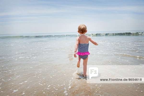 Weibliches Kleinkind  das ins Meer rennt.