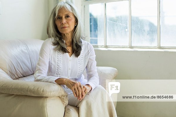 Porträt einer älteren Frau  die in der Wohnung sitzt