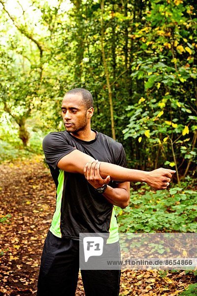 Man stretching arms in woods