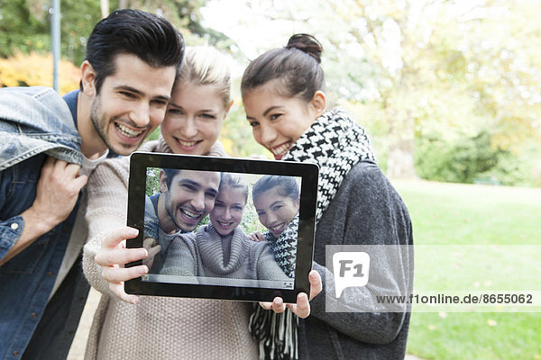 Freunde  die sich mit einem digitalen Tablett im Freien fotografieren.