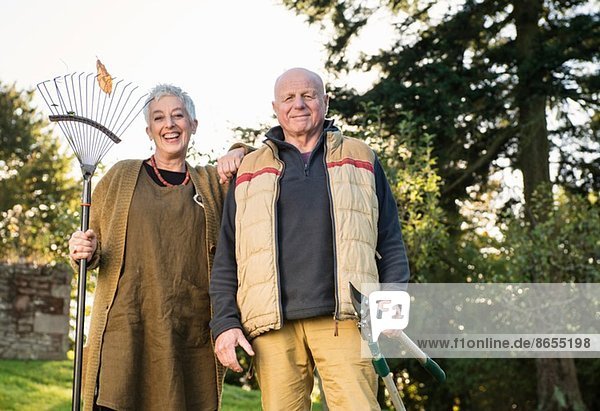 Senior couple holding rake and pruner