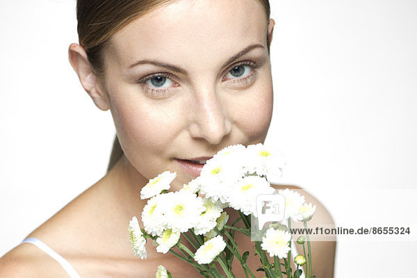 Young woman smelling bouquet of daisies