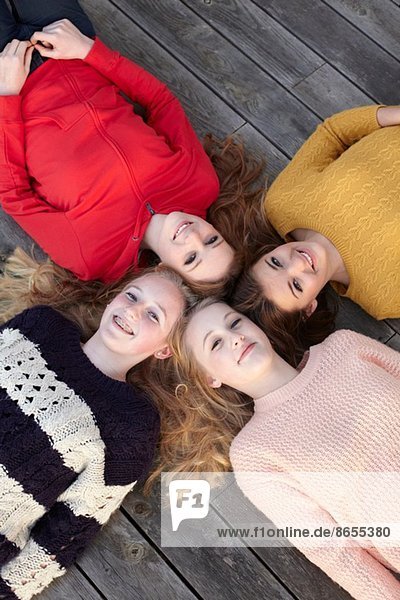 Porträt von vier Teenager-Mädchen Kopf an Kopf auf der Terrasse