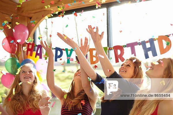 Vier Teenager-Mädchen feiern mit Konfetti auf der Geburtstagsfeier