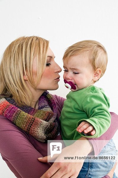 Studio-Porträt der Mutter  die versucht  die kleine Tochter zu beruhigen.