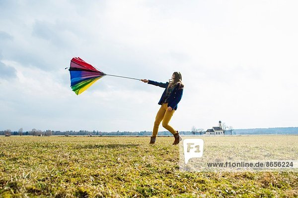 Teenage girl in field with umbrella