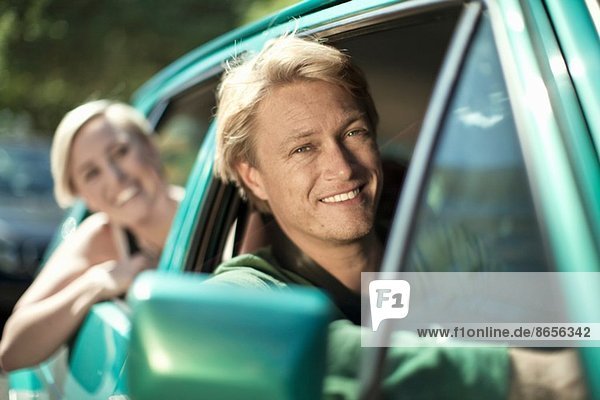 Junge Männer und Frauen die sich aus dem Autofenster lehnen.