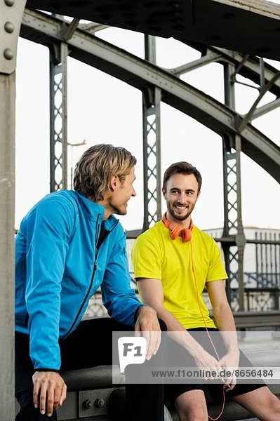 Zwei männliche Läufer im Gespräch auf der Brücke