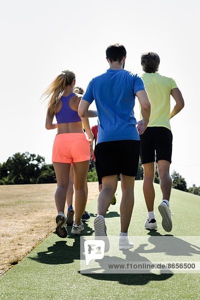 Reife Trainerin beim Laufen mit Erwachsenengruppe im Park