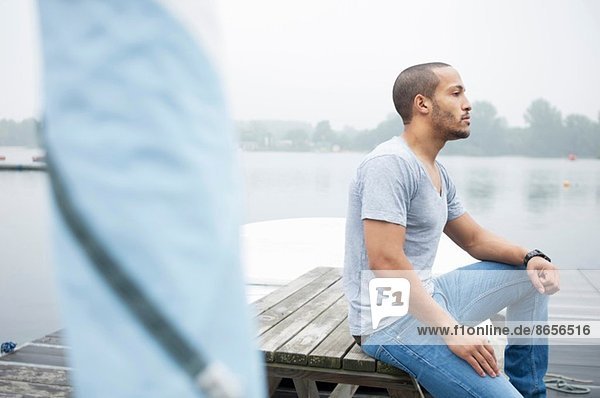 Young man sitting on jetty
