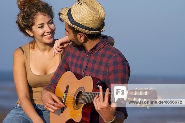 Young couple  man playing guitar