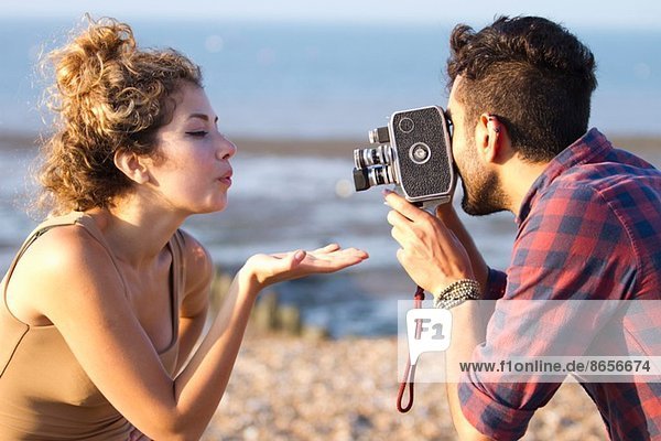 Young man filming woman with vintage camera