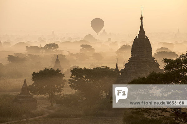 Hot air balloon over the landscape in the early morning fog temples stupas pagodas temple complex Plateau of Bagan Mandalay Division Burma or Myanmar