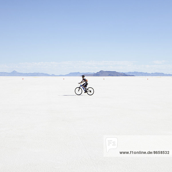 Junge fährt Fahrrad auf Salzebenen,  während der Speed Week