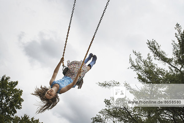 Ein Mädchen auf einer Seilschaukel  hoch in der Luft