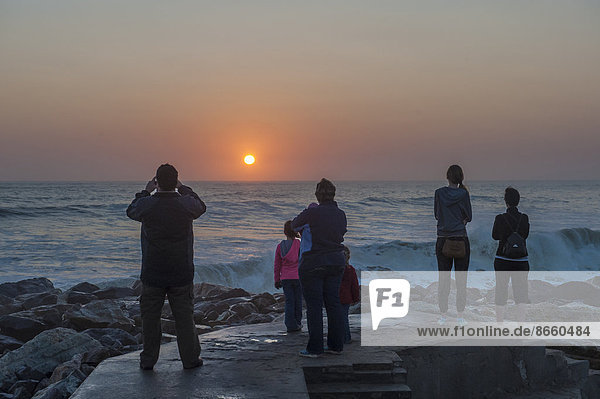 Menschen beobachten den Sonnenuntergang über dem Meer  Swakopmund  Region Erongo  Namibia