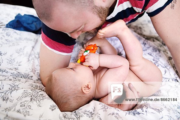 Father with baby son playing on bed  London  United Kingdom