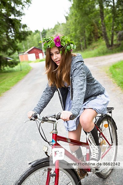 Teenage girl wearing flower wreath cycling  Nykoping  Sodermanland  Sweden