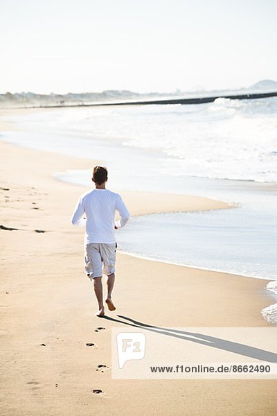 Mid adult man running on beach