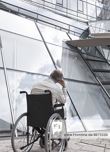 Älterer Mann sitzt im Rollstuhl vor einem modernen Gebäude  Niedersachsen  Deutschland