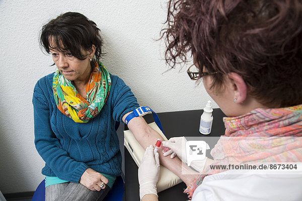 Arztpraxis  Patientin bekommt von einer Praxisassistentin Blut abgenommen  Deutschland
