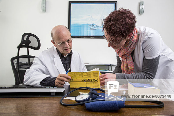 Arztpraxis  Arzthelferin und Arzt schauen sich gemeinsam eine Patientenakte an  Deutschland
